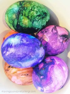 A bowl of colorful shaving cream dyed Easter eggs. The eggs are vibrant marbled blue. purple, green and pink.