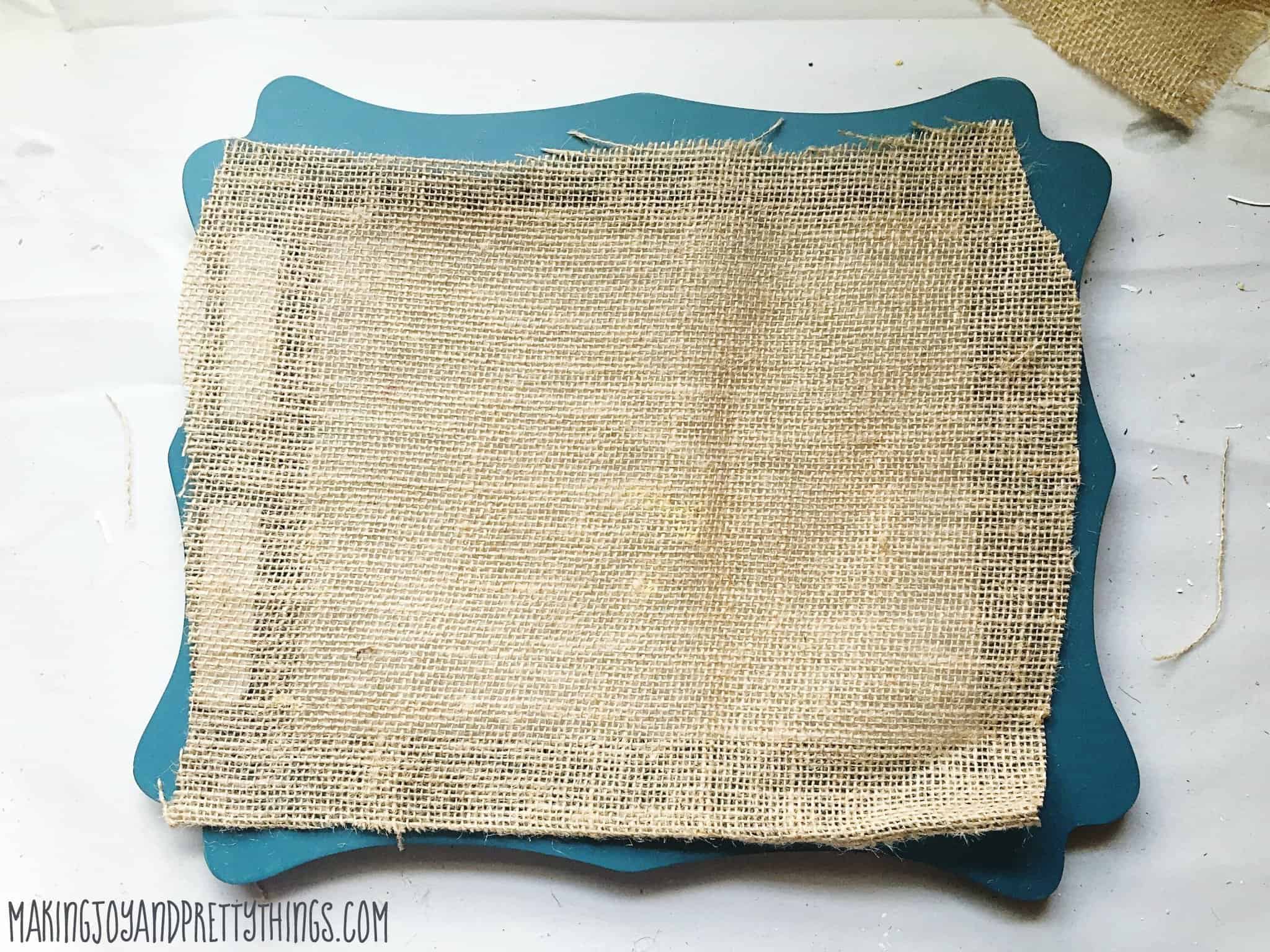 Cutting burlap to use as a backer for a DIY picture frame tray to hold decor items and use in a room as decoration