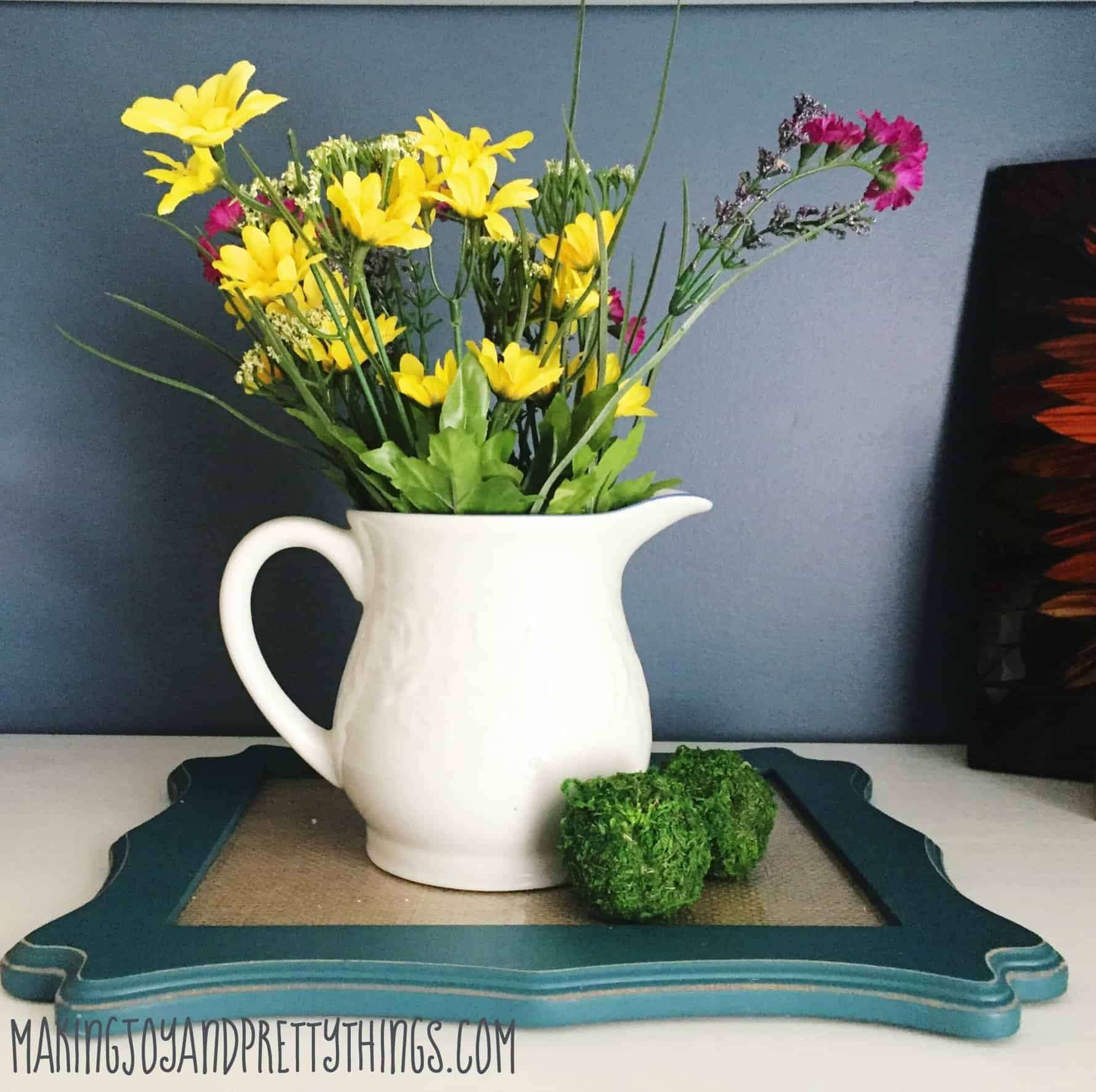 Pitcher with faux flowers and moss balls on top of glass using free items around the house