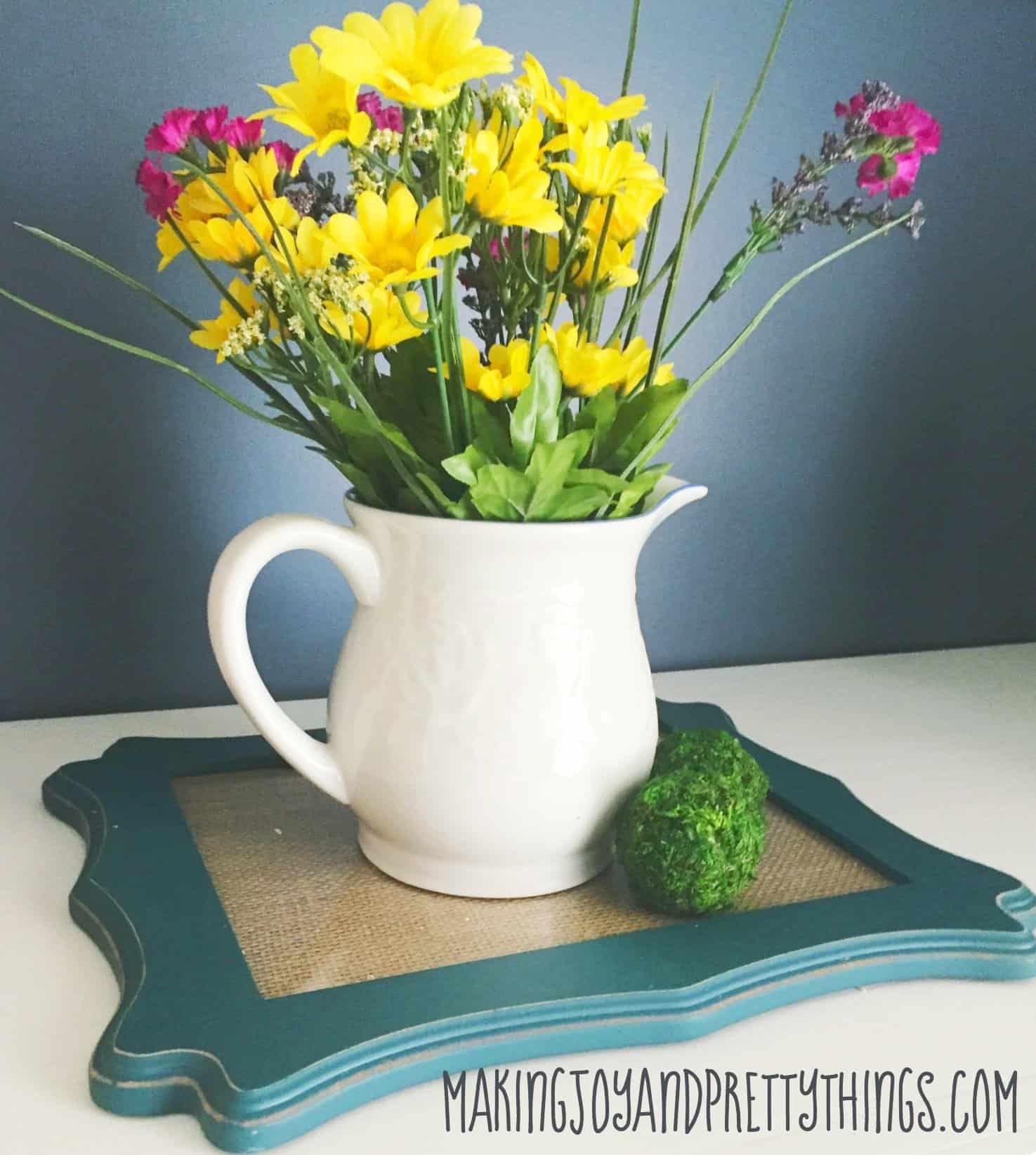 Beautiful arrangement of faux flowers inside a pitcher on top of a DIY picture frame tray