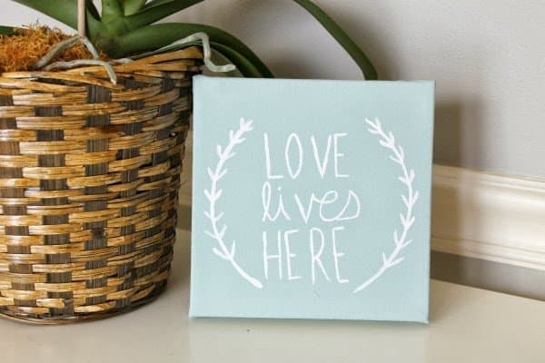 Love lives here sign made as a farmhouse diy project that shown off next to a plant