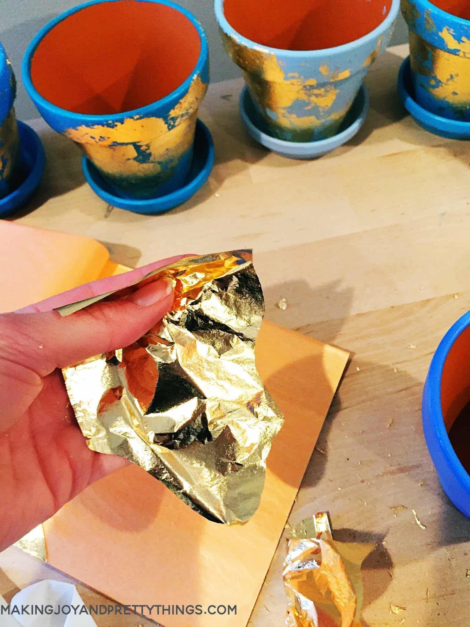 Spray the pots and gold foil in order to apply the leaf look to the planters transformed from terra cotta pots