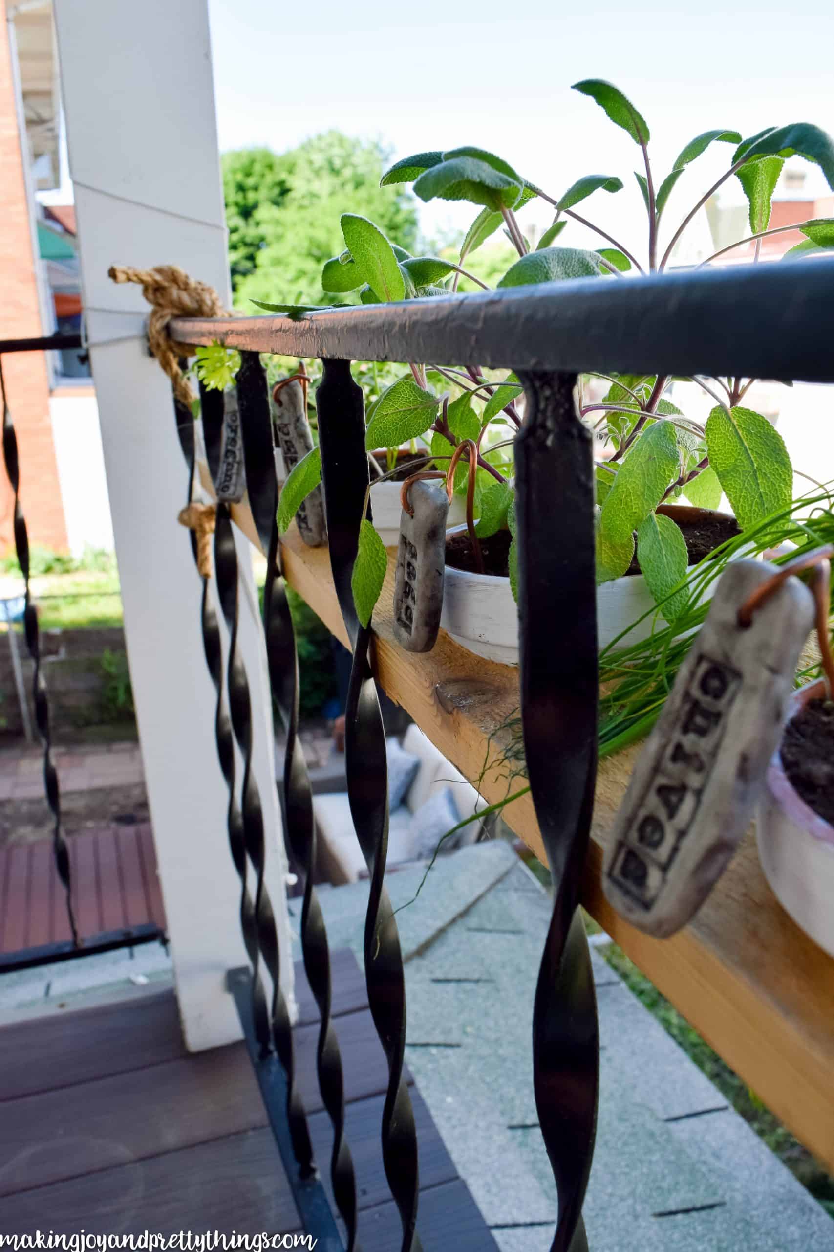 row of plants tied to a balcony with a rustic farmhouse look labeled with markers