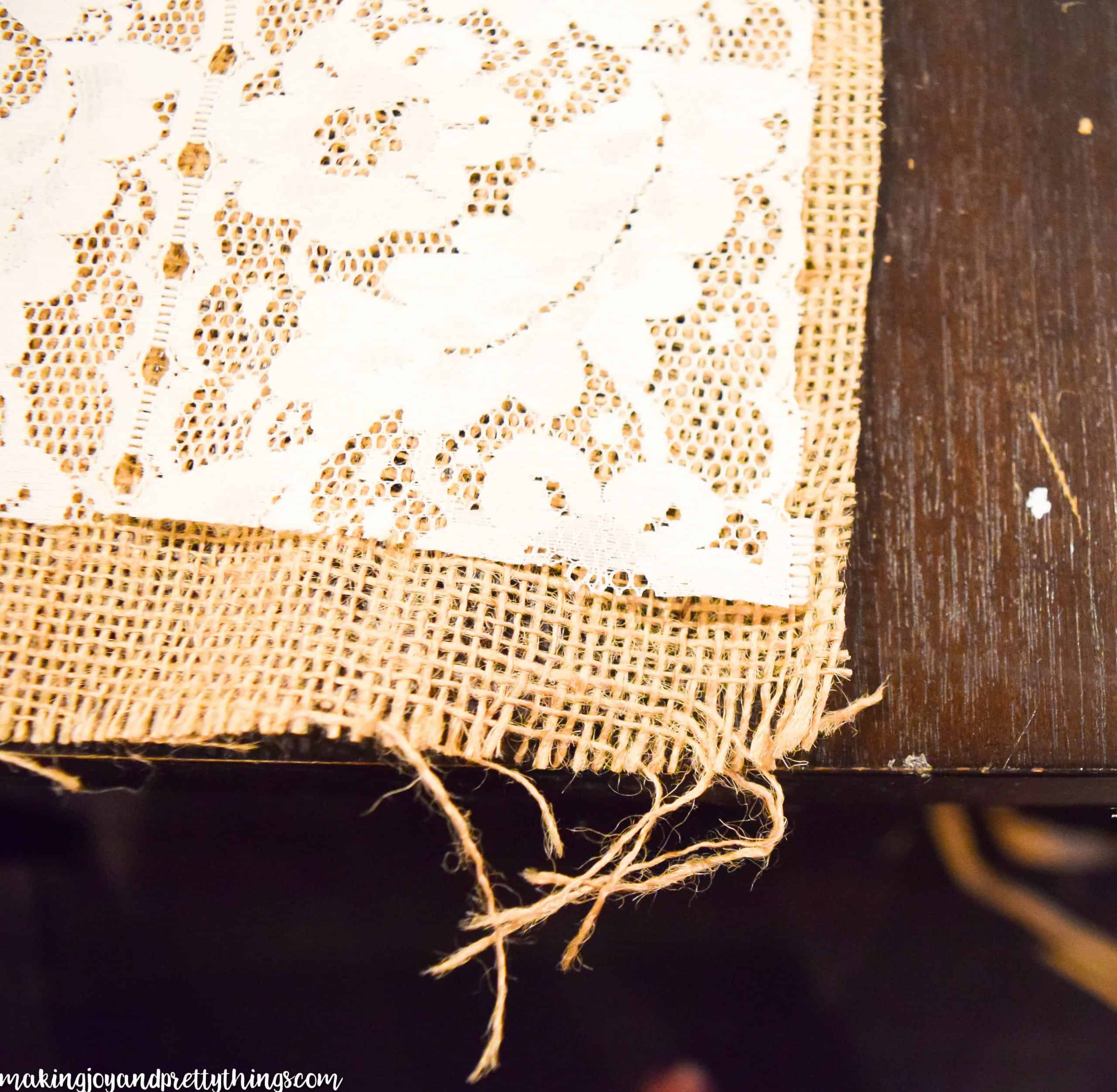 A close up look at the torn ends of the burlap and lace table runner. The ends of the burlap fabric are frayed for a more rustic look.