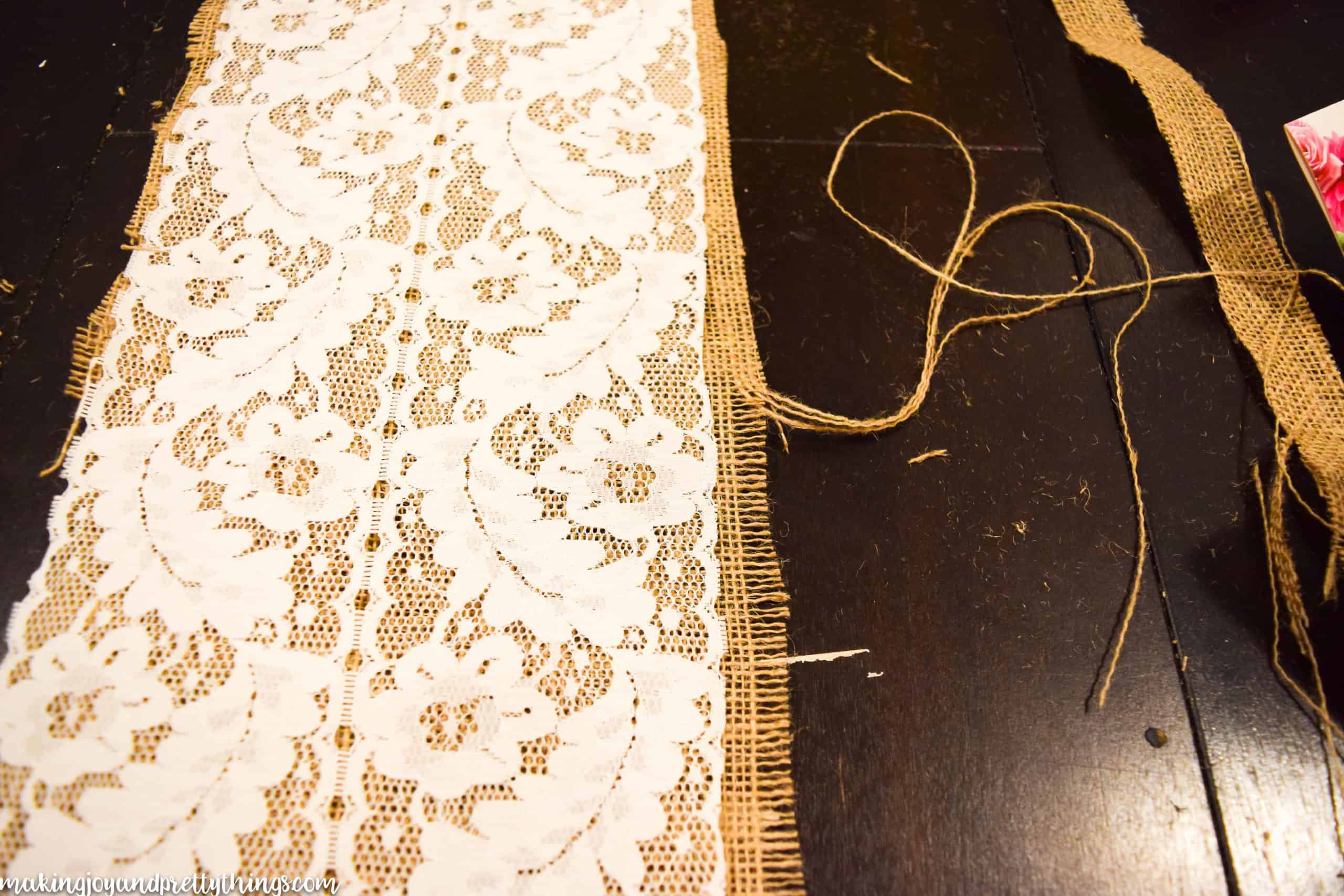 A look at the process of fraying the edges of the burlap table runner to give it a more rustic look. Strings of burlap fabric are pulled from the right side of the runner.