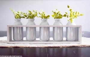 A farmhouse centerpiece made with painted milk jars filled with faux greenery.