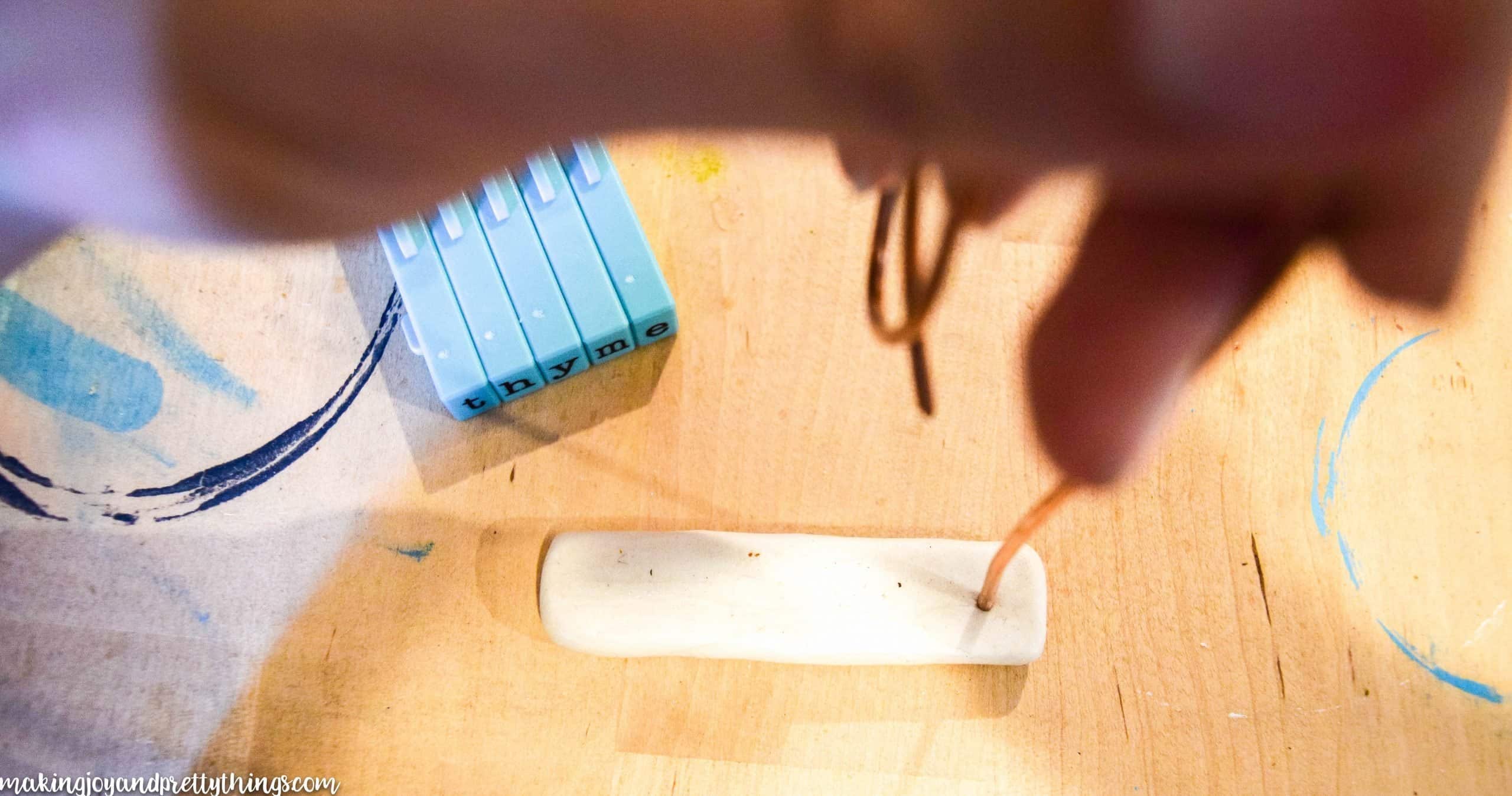 making a hole with copper wire in oven backed clay before baking to have a tag hole to hang the diy plant labels