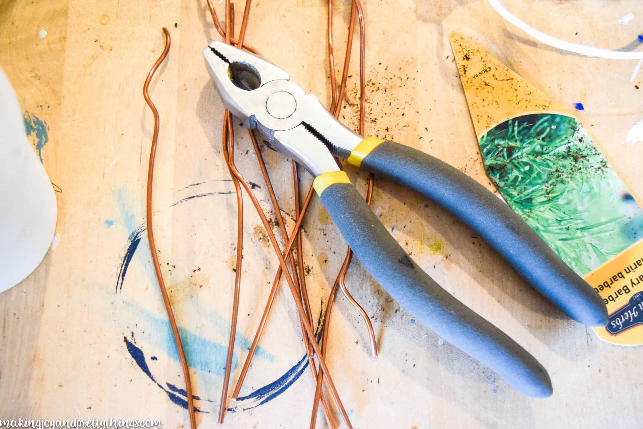 Linesman pliers and copper wire to make tag holders for potted plants by bending and shaping the copper wire