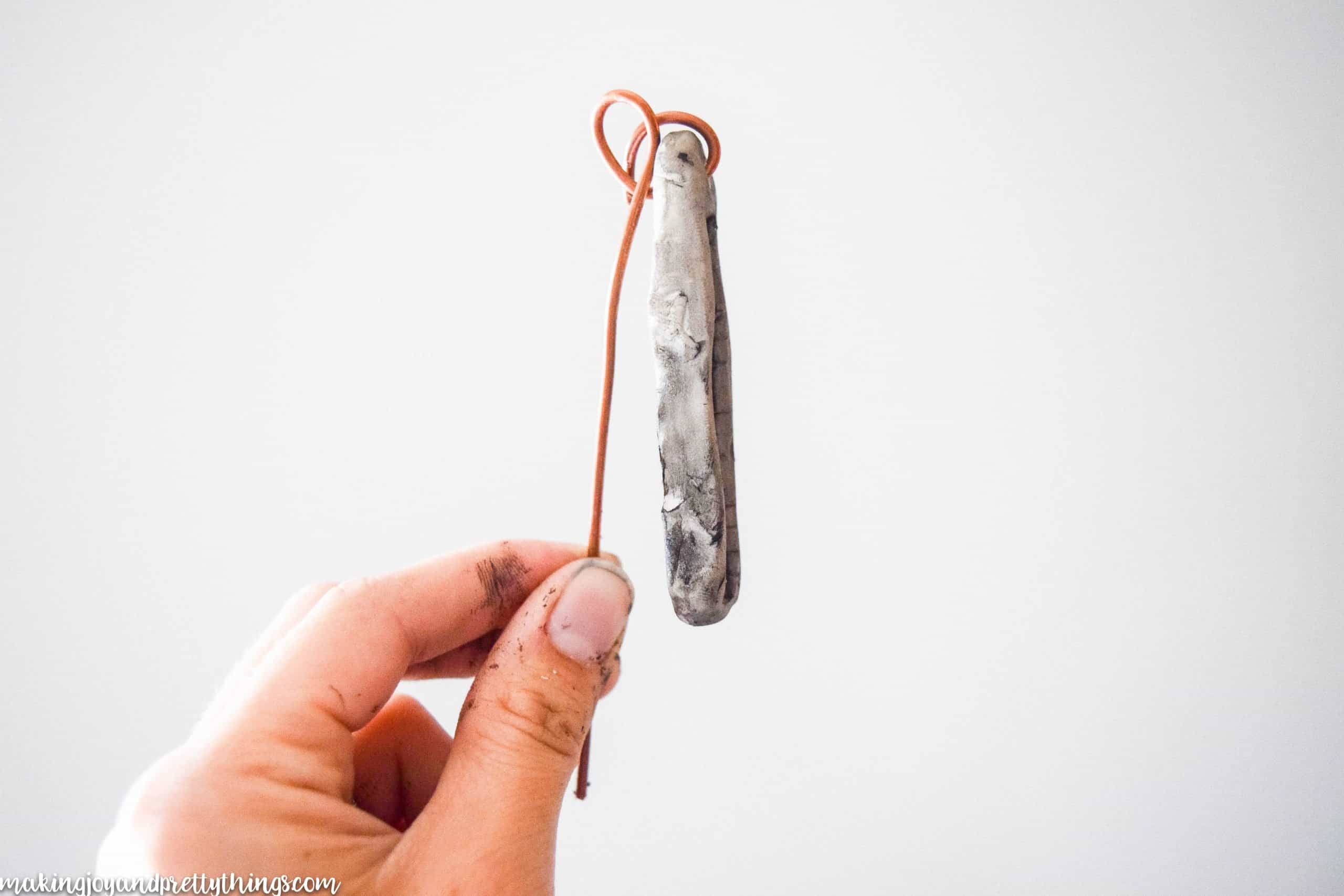 Shaping copper wire around a DIY plant label by twisting loops to secure the tag and put into a potted plant