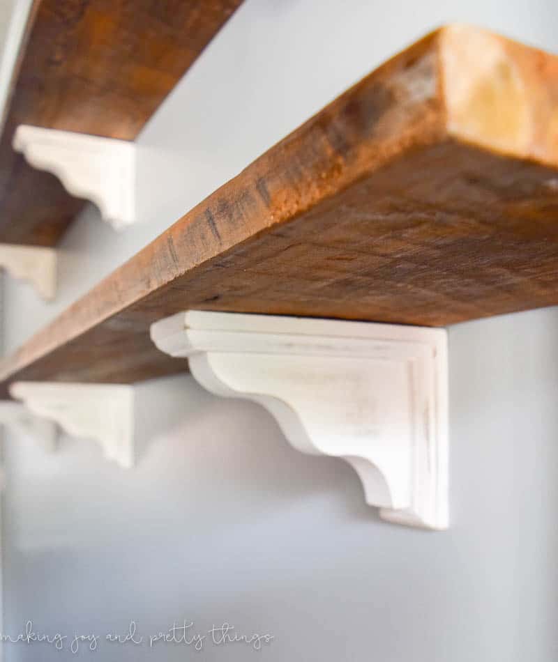 Close up of the corbels supporting the DIY farmhouse shelves in a rustic vintage look made by distressing wood