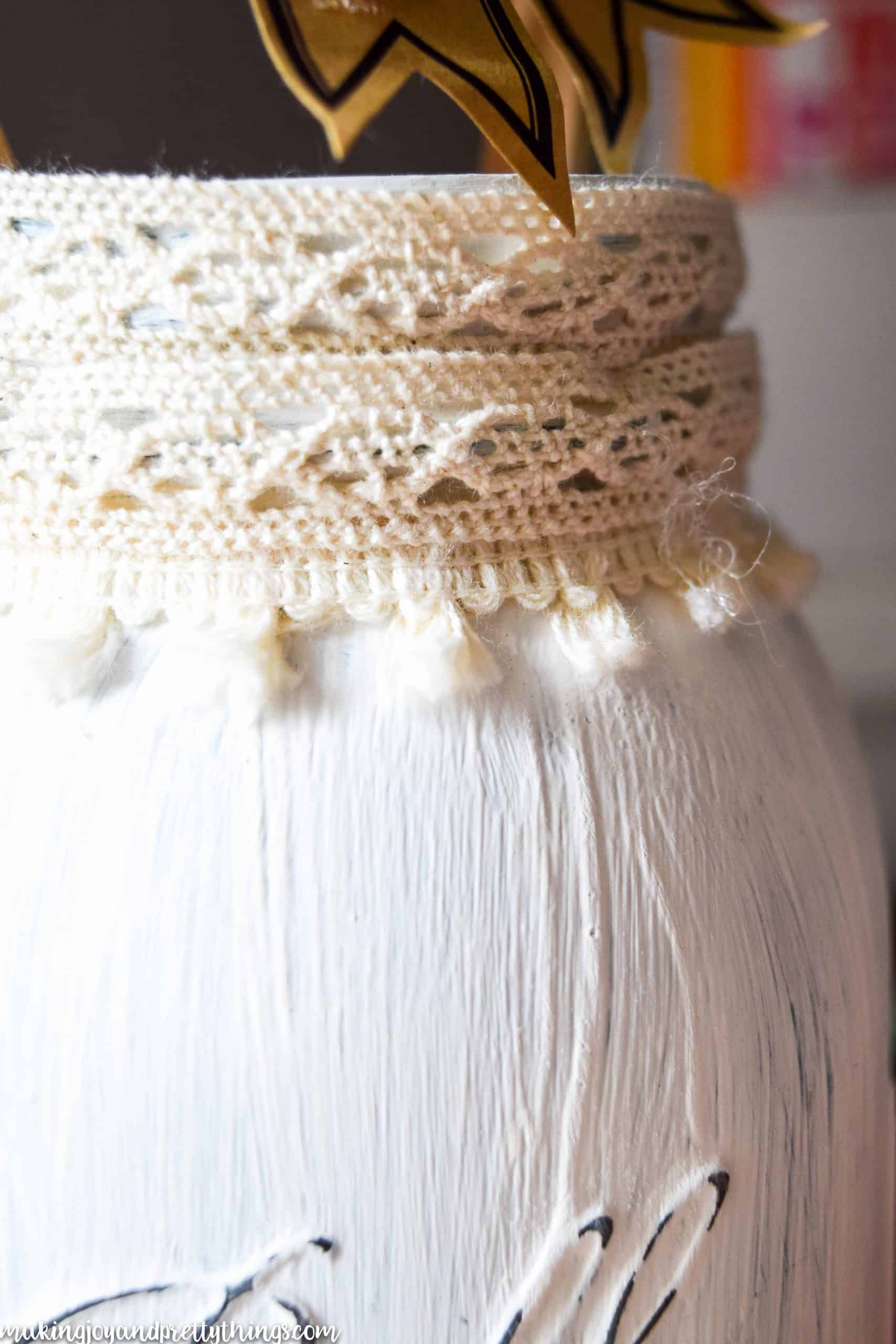 Ivory trim around the mouth of a mason jar that has been painted white and distressed