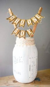 A white painted mason jar with a "choose joy" banner made from paper.