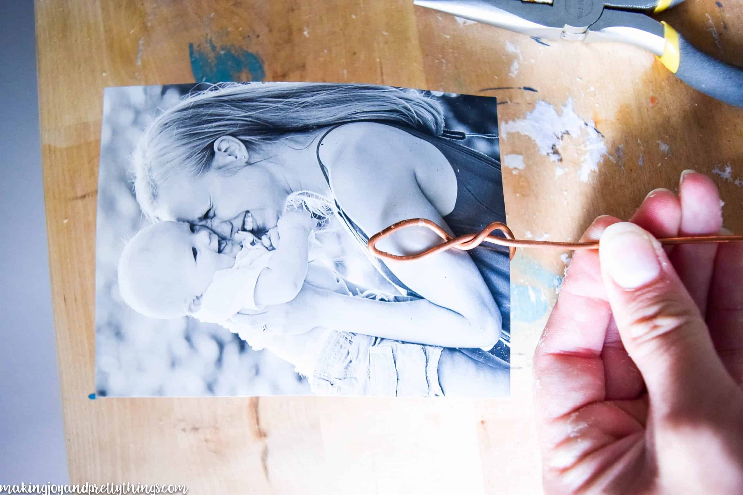DIY wire photo holder made from copper looped to hold a photo of a mother and baby 