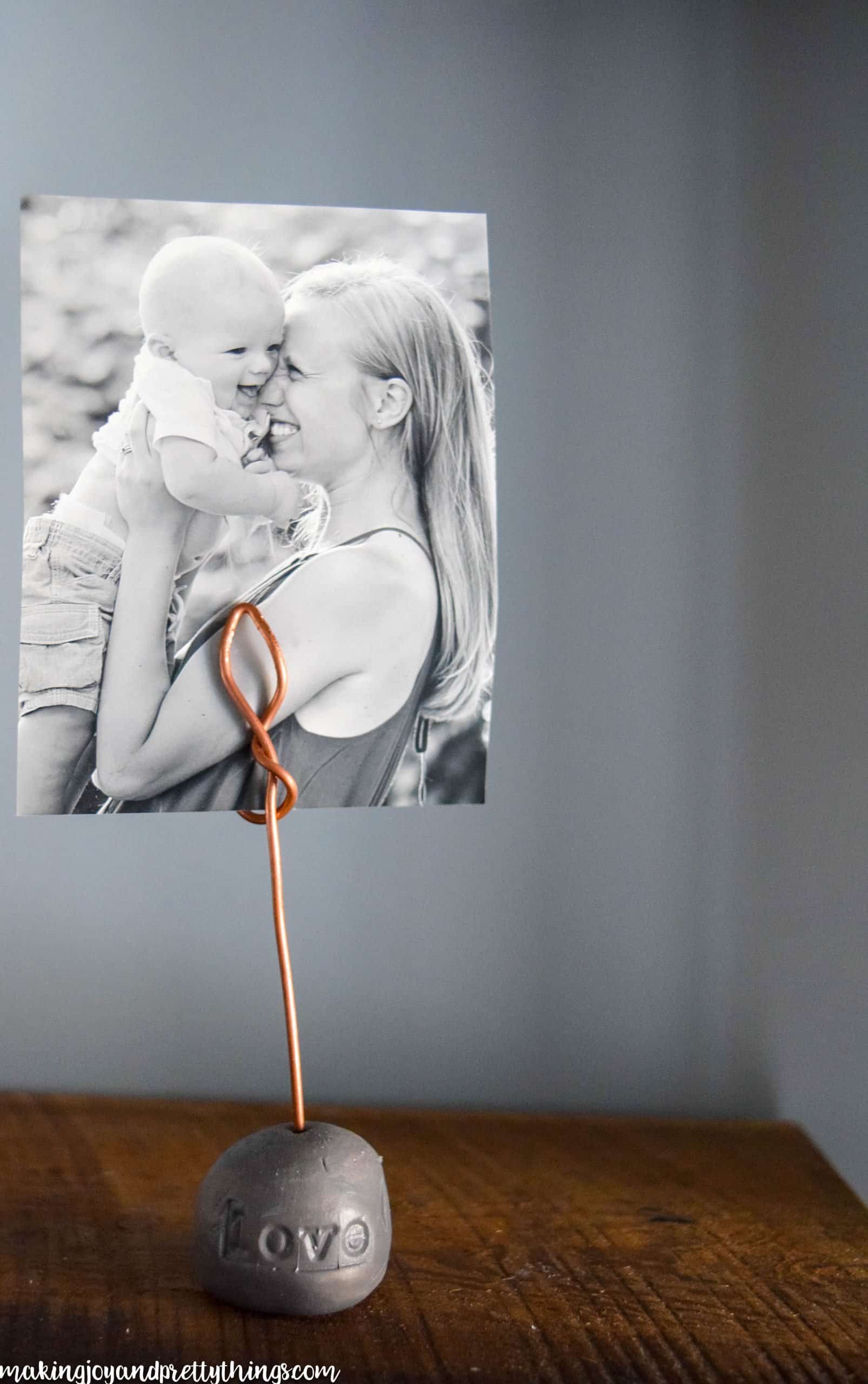 DIY wire photo holder on a rustic shelve desk with farmhouse finishes and a picture of a mother and child