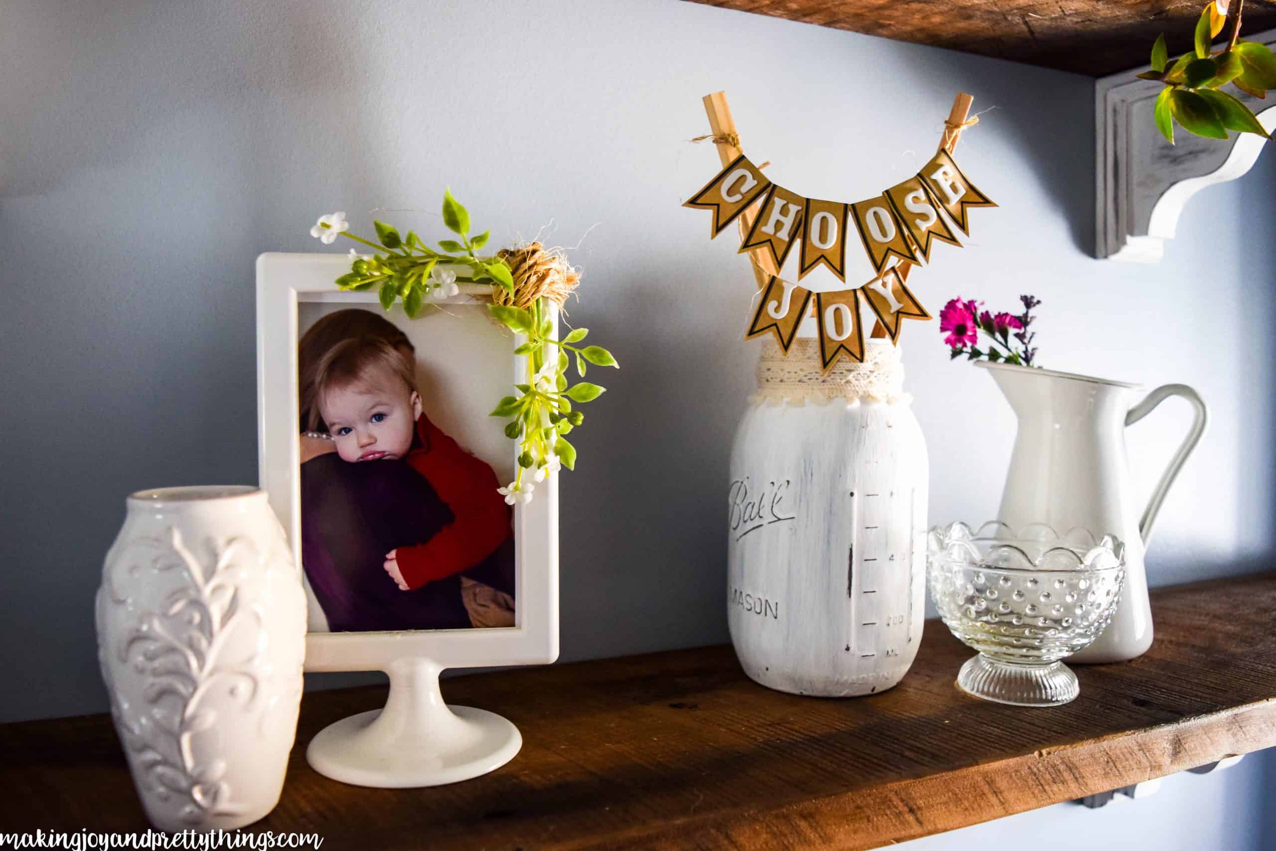 DIY mason jar display on farmhouse shelving next to a picture and other decor items 