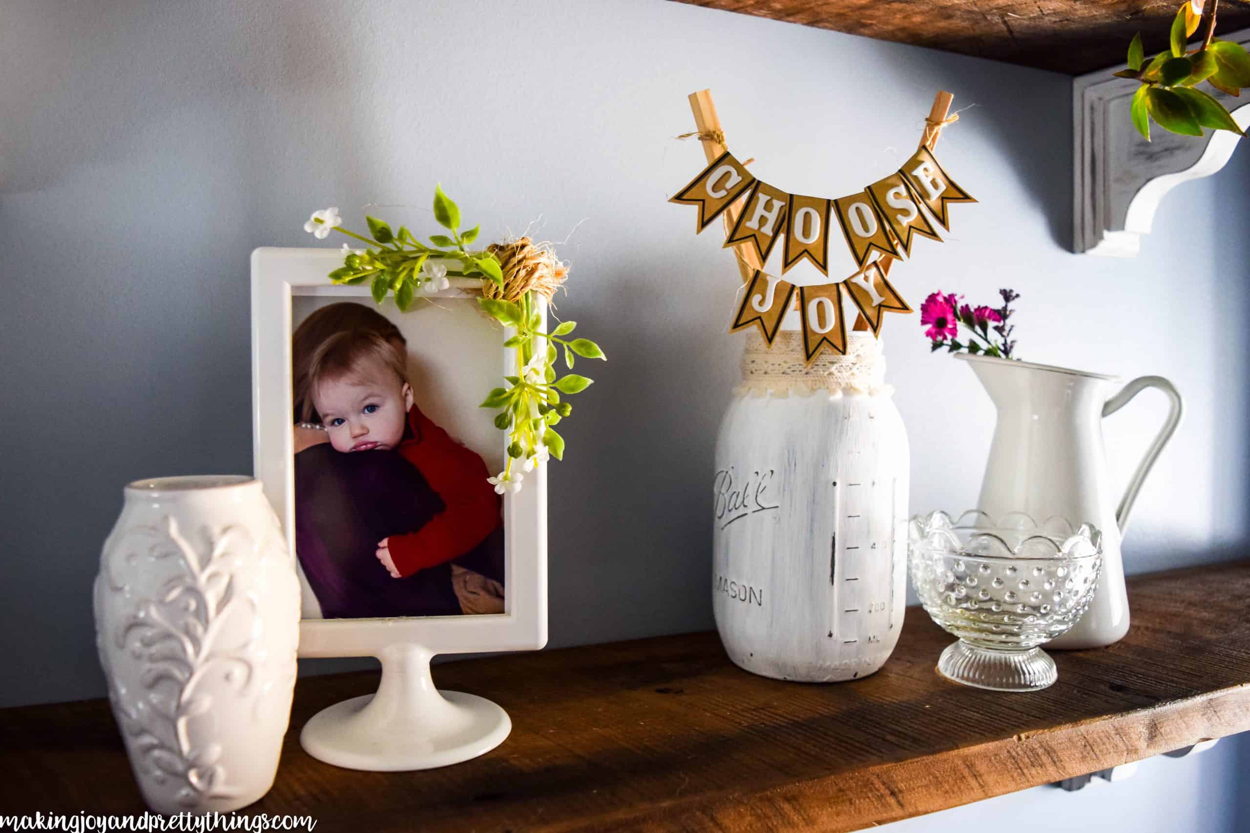 DIY mason jar display on farmhouse shelving next to a picture and other decor items