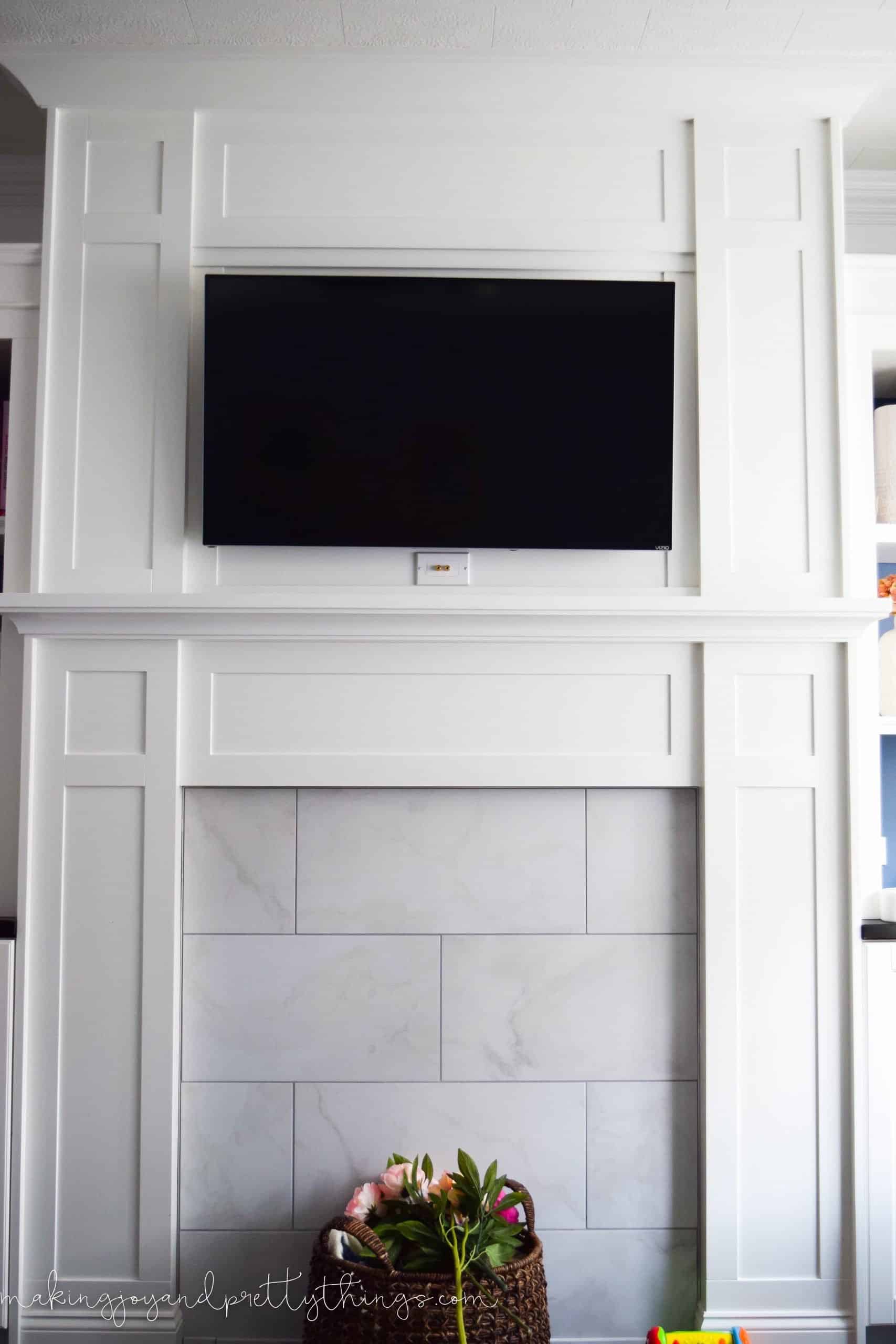 A complete look at our white wood mantle, with wall-mounted TV and marble tiled fireplace hearth. 