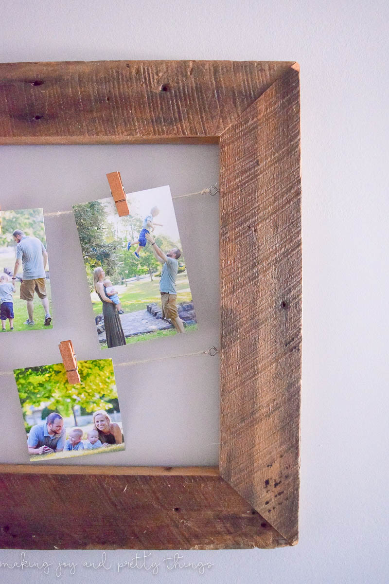 A close up look at the rustic details on the reclaimed barnwood used to make this DIY rustic picture frame. You can also see some family photos clipped to strings of twine with clothespins.