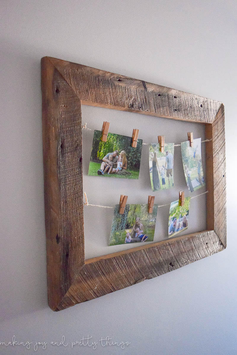 A DIY rustic wood picture frame made from barnwood holds five family pictures, hanging on twine with clothespins.