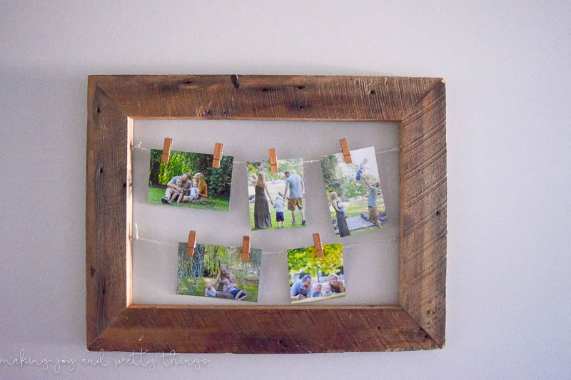 Rustic frame made with barn wood with string hanging on the inside of the frame with clothespin clips holding family photos