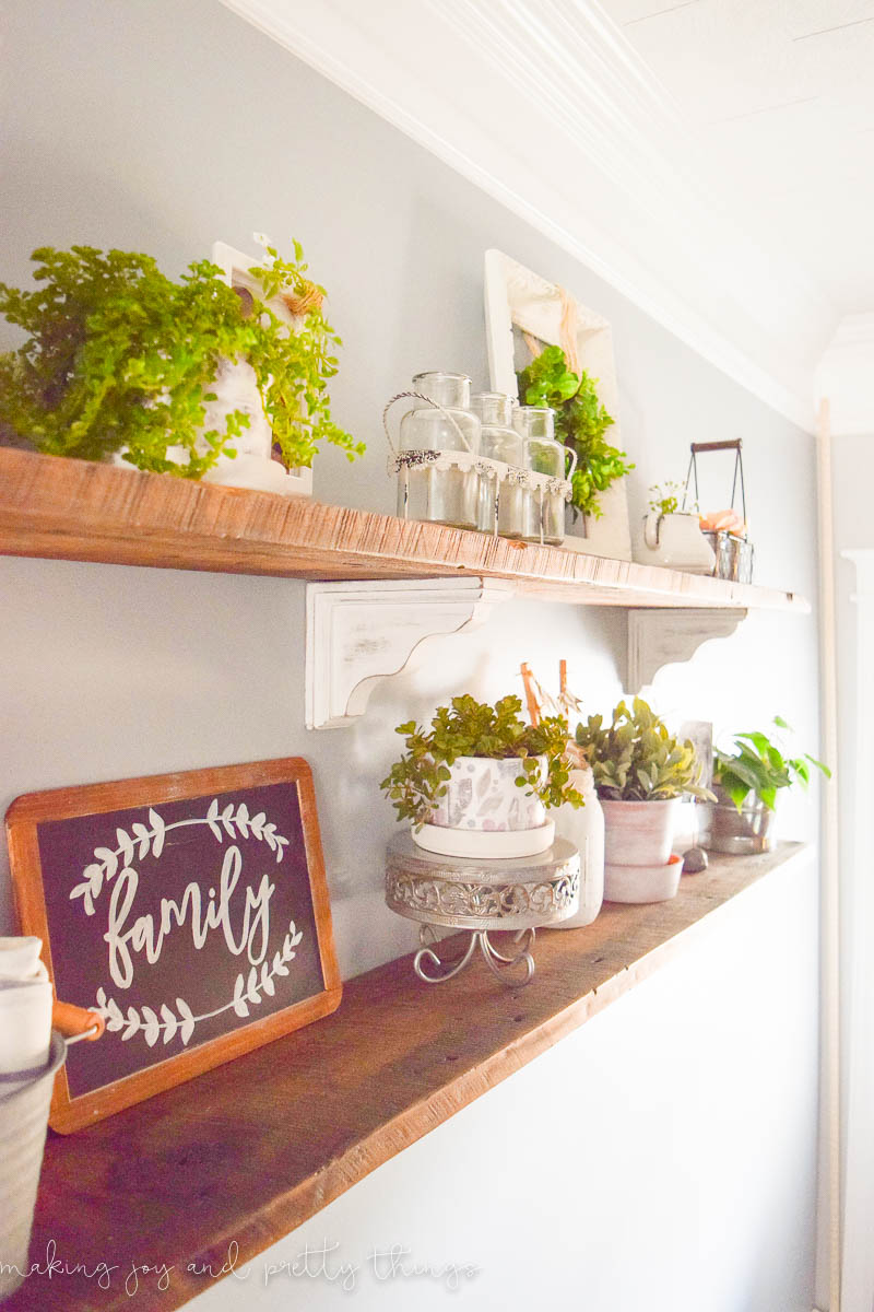 Close up of DIY hanging that have been decorated with chalkboard, plants, pots, and other decor in a farmhouse style