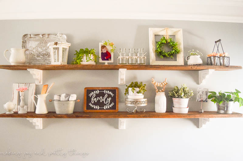 Completed shelves for a how to style open shelves tutorial in a living room hung up on a wall with Corbels