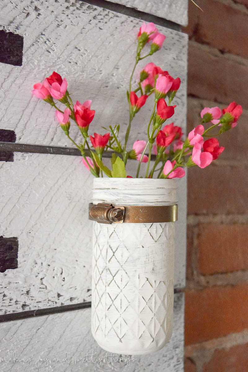 I love this cute idea of mounting painted mason jars to a wood sign and adding faux flowers to add some instant life to your space