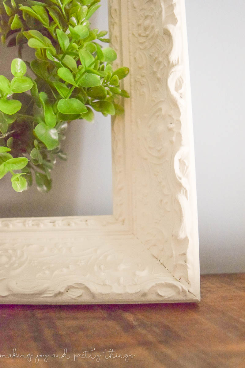 A close up look at the ornate wood details of the thrifted wood frame used to make this DIY wreath hanger. 