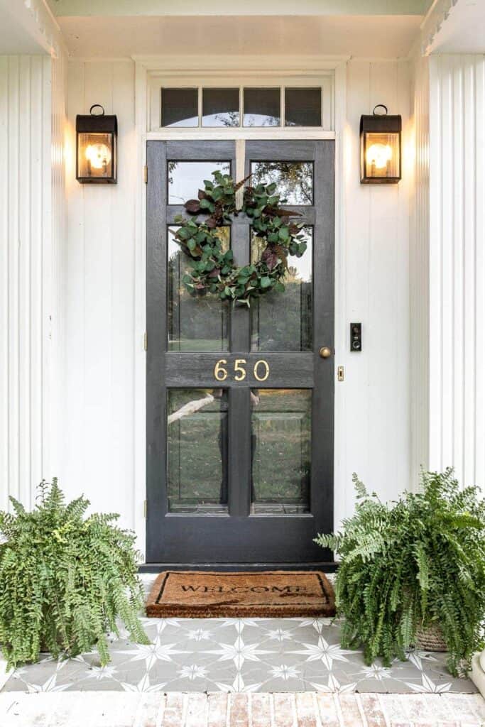 Beautiful greenery leaf with fall color notes hung on a black front door to kick off the early fall season