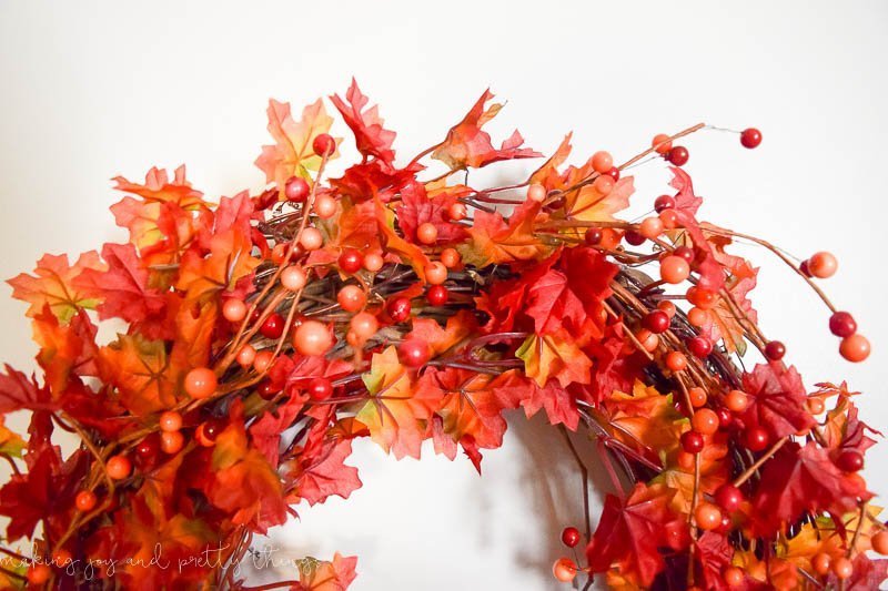 The top of a DIY fall leaf wreath with colorful orange and red leaves and berries. 