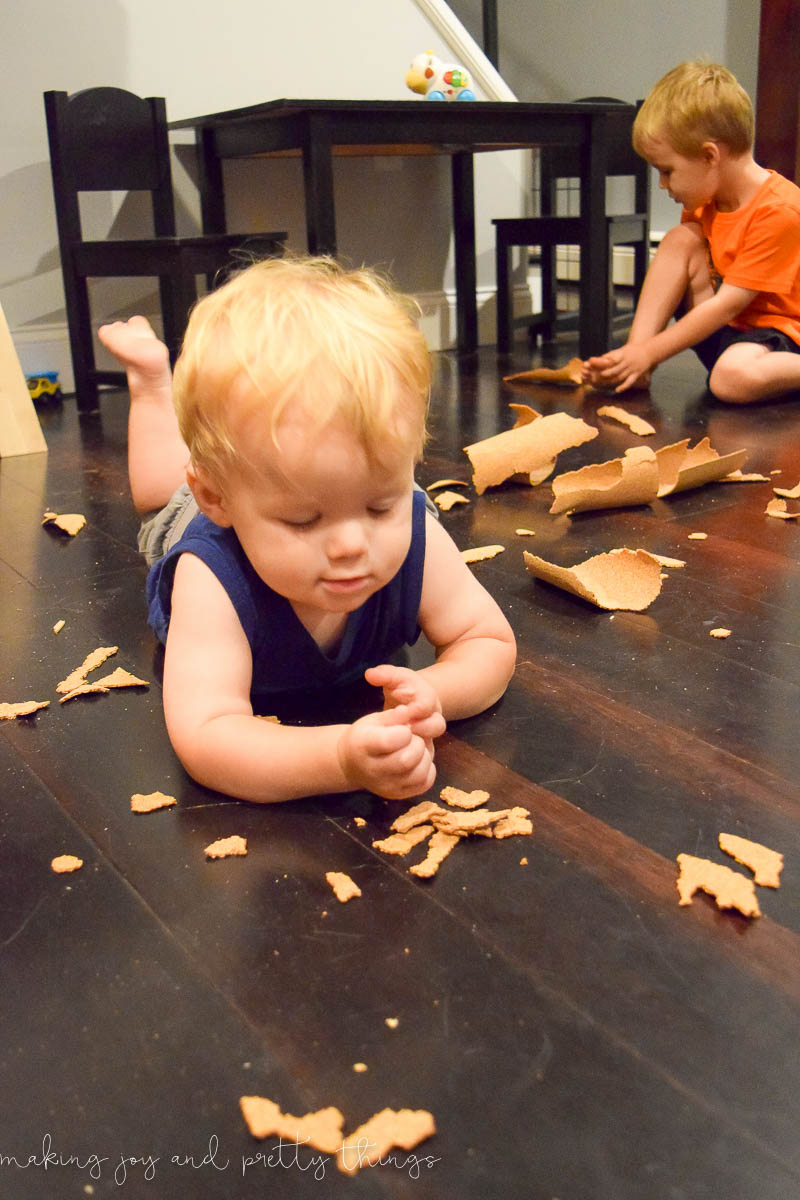 Two young boys tearing apart cork board that was previously used for an organization tool for an office