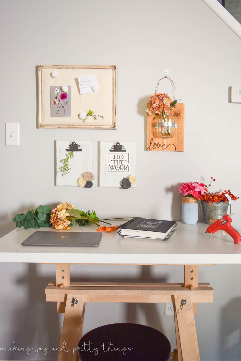 Rustic farmhouse craft area with desk made with a sawhorse and wall decor including a memo board, diy clipboards and a mason jar hanging