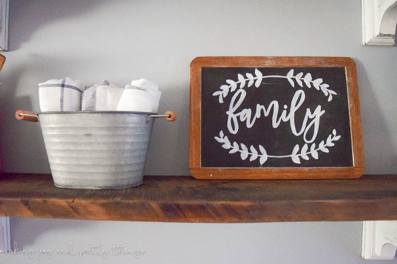 DIY chalkboard lettering on a framed chalkboard from michaels done in a pretty font on rustic shelves