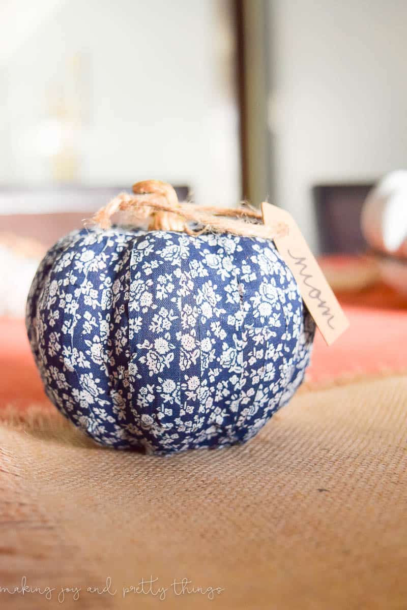 A small fabric pumpkin covered in blue and white floral patterned washi tape serves as a placecard at our dining room table.