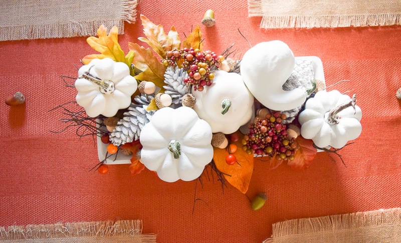 An overhead view of the traditional fall centerpiece on our dining room table. The centerpiece is filled with faux white pumpkins, acorns, leaves, berries, and more.