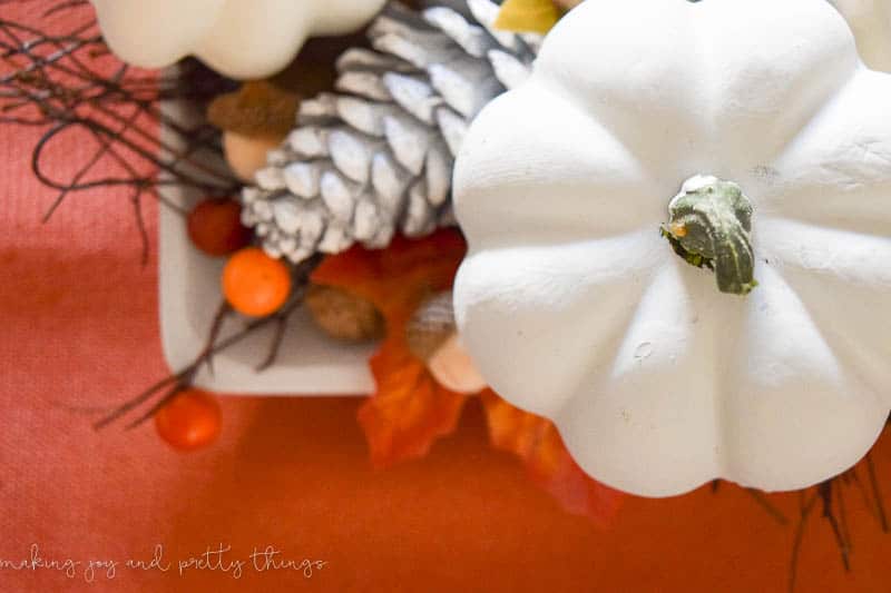 A close up overhead view of the faux white pumpkins in the fall-themed centerpiece on our dining room table.
