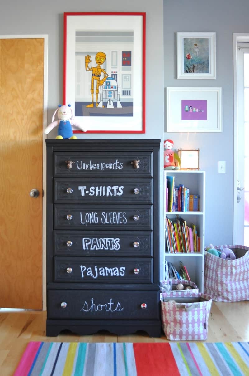 A black dresser in chalkboard paint with labeled drawers to organize a shared kids room and keep clean