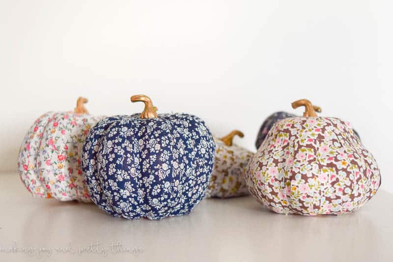 Five small craft pumpkins with gold stems, each covered in washi tape, each with a different floral pattern.