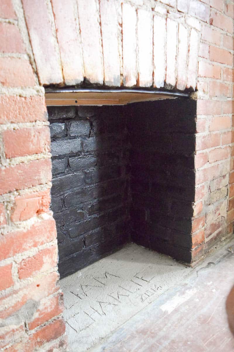 A look at our natural brick fireplace in the middle of a makeover. The inside of the fireplace is painted black, and we leveled out the floor using quick-set concrete.