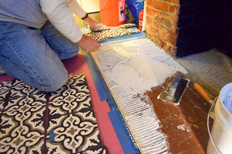 Spreading tile mortar on the fireplace hearth before installing the cement tiles.