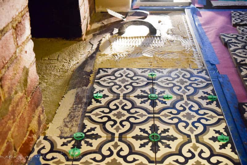 The process of installing cement tiles on our fireplace hearth - these black, white and gray tiles are installed using mortar and tile spacers for perfectly-set tiles.