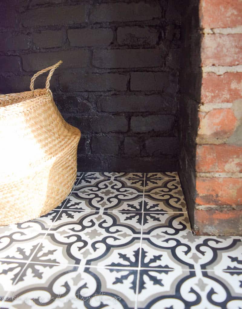 A closer look at our completed fireplace - with black, white, and gray patterned tiles, natural brick painted black, and a decorative woven basket.