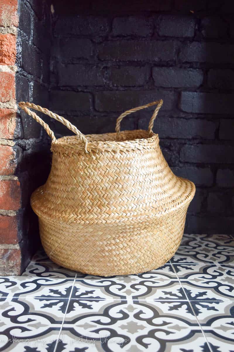 A close up look at the decorative woven basket sitting on the fireplace hearth and new black and white patterned cement tiles.