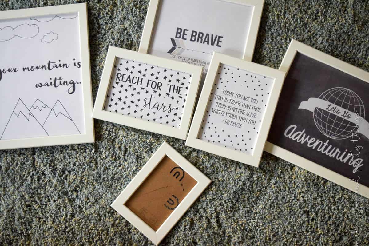 White picture frames sit on grey carpet. Each picture frame holds a picture with an inspirational saying printed on it.