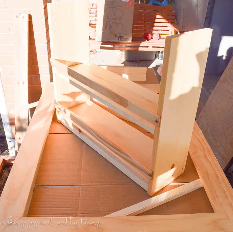 An in-progress photo of building the side storage racks for the kids crafting table. Two small wooden shelves sit on a work surface.