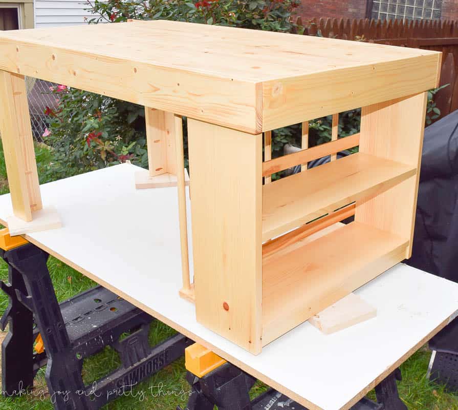 The completed kids craft table made with unstained pine wood, a built-in bookshelf and plenty of storage for toys and craft supplies.