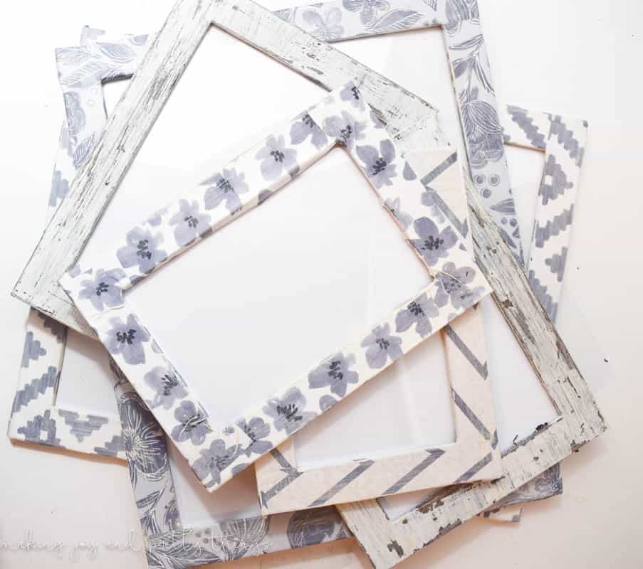 A set of DIY farmhouse picture frames for a gallery wall. The frames are all different sizes and covered in modpodged craft paper, each with a different white and gray pattern.
