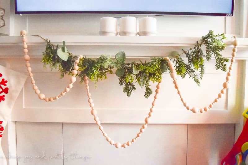 Create a farmhouse Christmas mantel with this easy to do garland idea using wood beads, twine, and floral