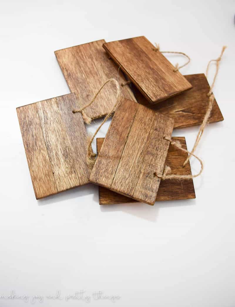 A pile of small pieces of wood, all stained with a dark wood stain, with pieces of twine attached to each piece of wood.