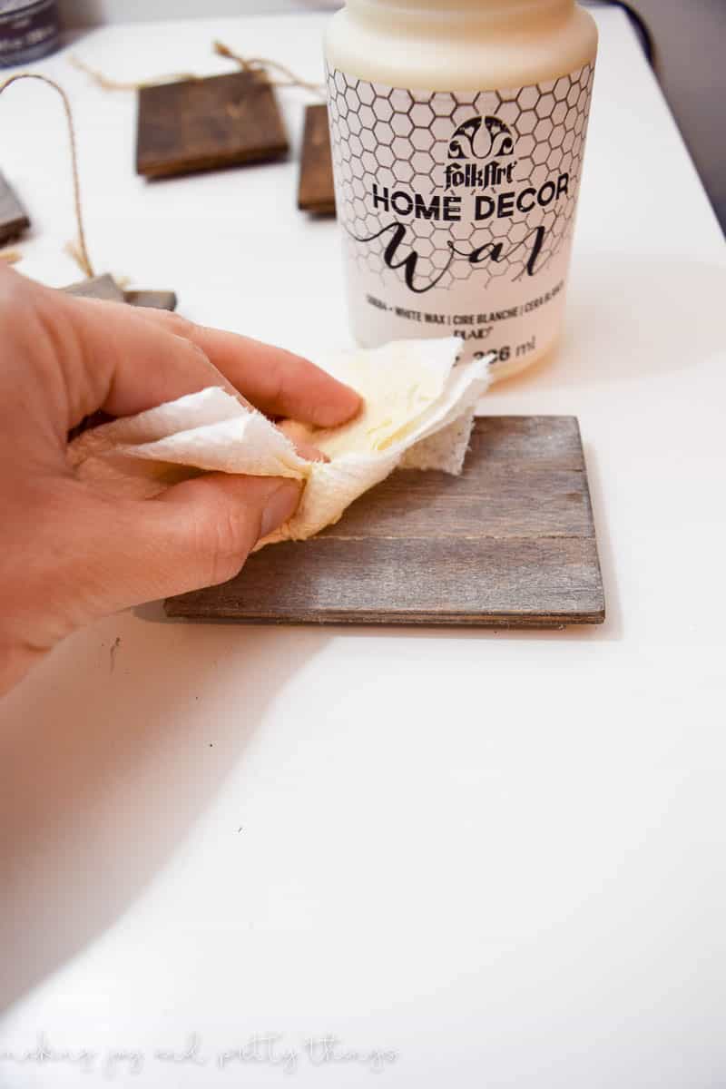 Using a paper towel to wipe the excess white wax coating from the small wood basket sign. This gives it a slightly whitewashed look.